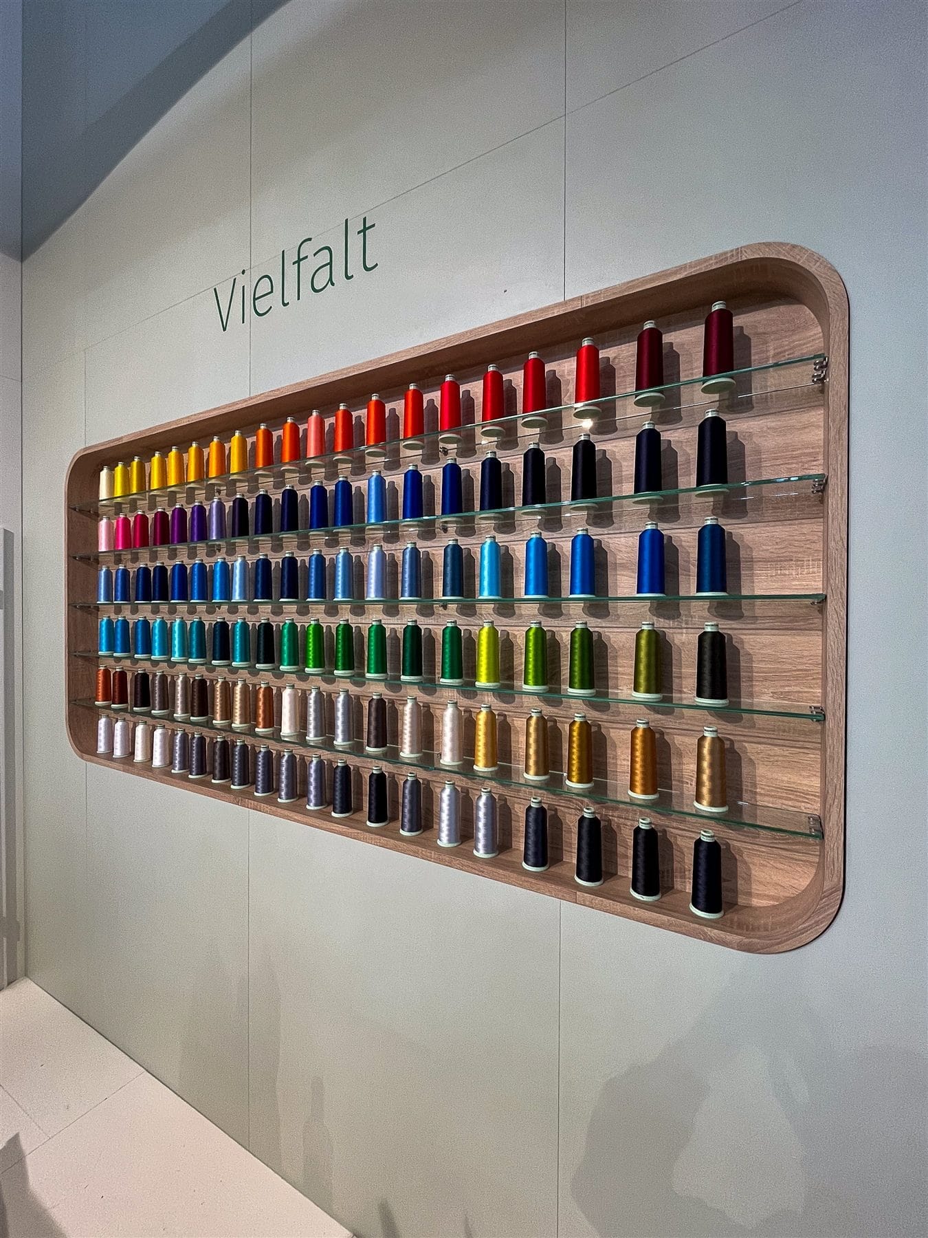 Wandregal mit hunderten farbigen Garnrollen im Madeira-Showroom